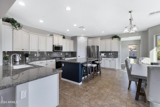 kitchen with sink, a center island, a notable chandelier, dark stone countertops, and appliances with stainless steel finishes