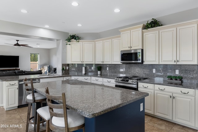 kitchen featuring ceiling fan, sink, kitchen peninsula, a breakfast bar area, and appliances with stainless steel finishes