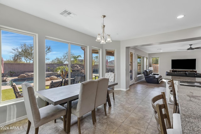 tiled dining space with ceiling fan with notable chandelier and a healthy amount of sunlight