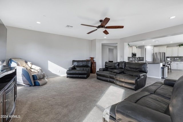 carpeted living room with ceiling fan and sink