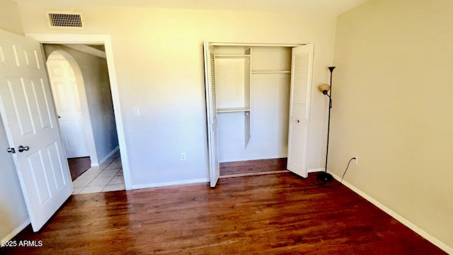 3404 W Tangerine Ln, Phoenix, AZ 85051 - unfurnished bedroom featuring a closet, wood finished floors, arched walkways, and baseboards