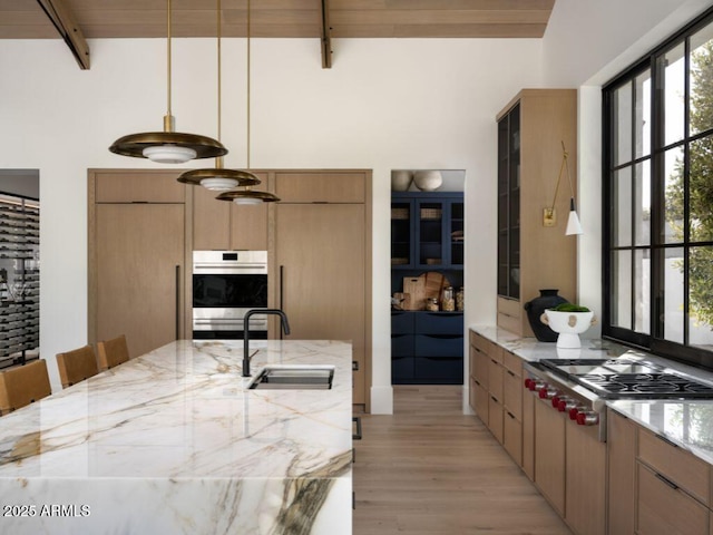 kitchen featuring stainless steel appliances, a sink, a kitchen breakfast bar, hanging light fixtures, and beam ceiling