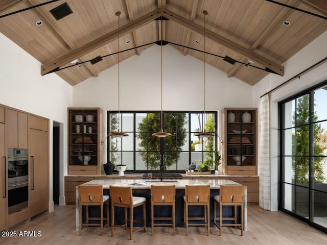 kitchen with high vaulted ceiling, beam ceiling, light countertops, and a large island