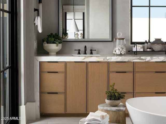 bathroom with a freestanding bath, double vanity, a sink, and tile patterned floors