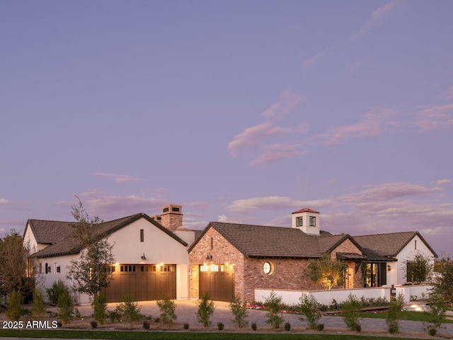 view of front of property featuring concrete driveway, a chimney, and an attached garage