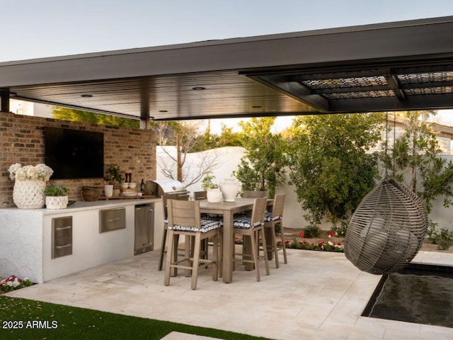 view of patio featuring fence, outdoor dining area, and exterior kitchen