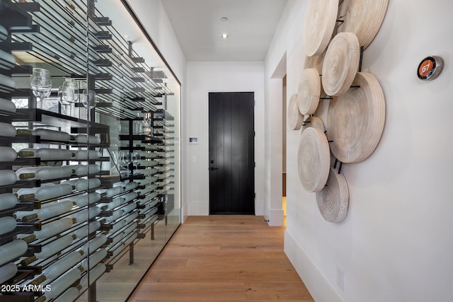 wine cellar featuring light wood finished floors, baseboards, elevator, and recessed lighting