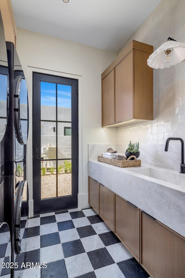 kitchen featuring dark floors, light countertops, backsplash, light brown cabinetry, and a sink