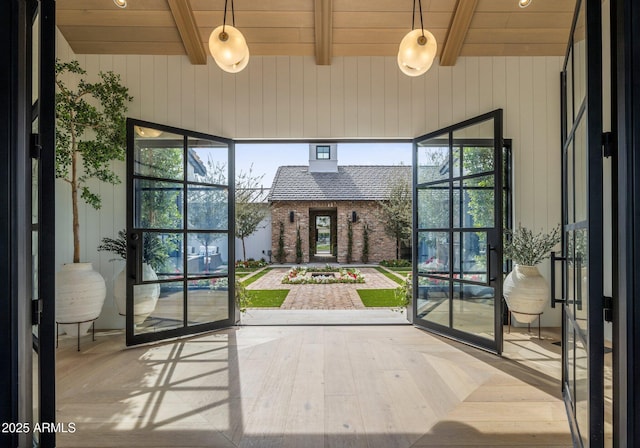 doorway featuring lofted ceiling with beams, light wood-type flooring, wooden ceiling, and a wealth of natural light