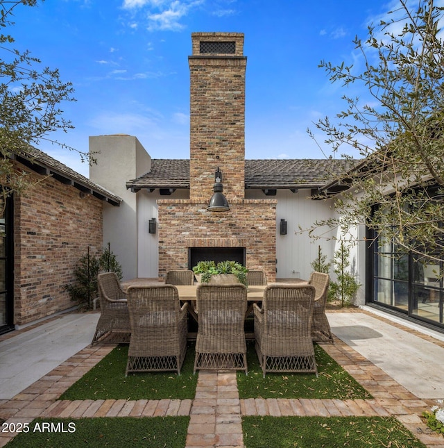 view of patio / terrace with an outdoor brick fireplace and outdoor dining area