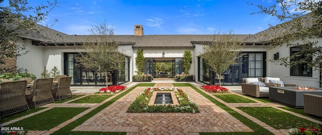 rear view of property featuring an outdoor living space with a fire pit, a chimney, and a patio