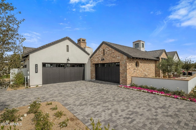 view of side of property with a garage, decorative driveway, brick siding, and fence