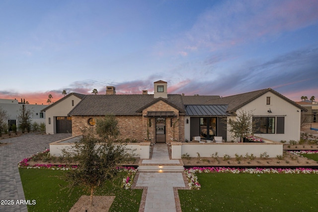 view of front facade with a standing seam roof, a yard, metal roof, and brick siding