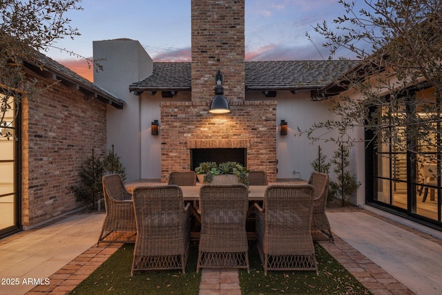 view of patio with a brick fireplace and outdoor dining space