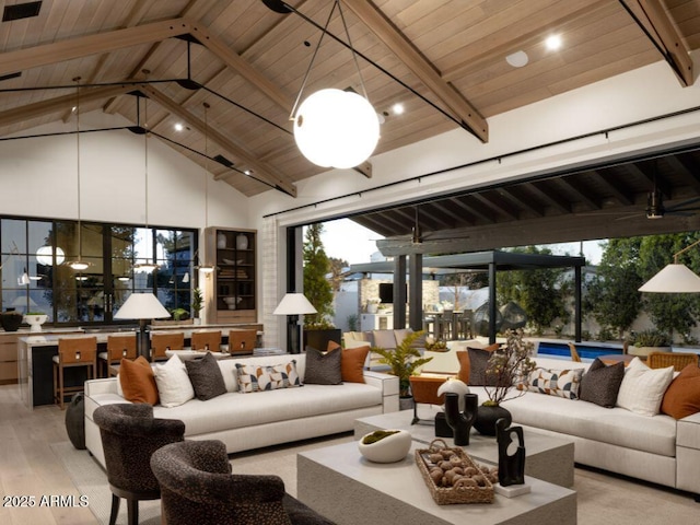 living area with ceiling fan, high vaulted ceiling, wooden ceiling, beam ceiling, and light wood finished floors