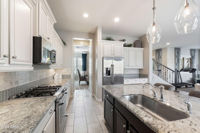 kitchen featuring pendant lighting, white cabinets, sink, appliances with stainless steel finishes, and light stone counters