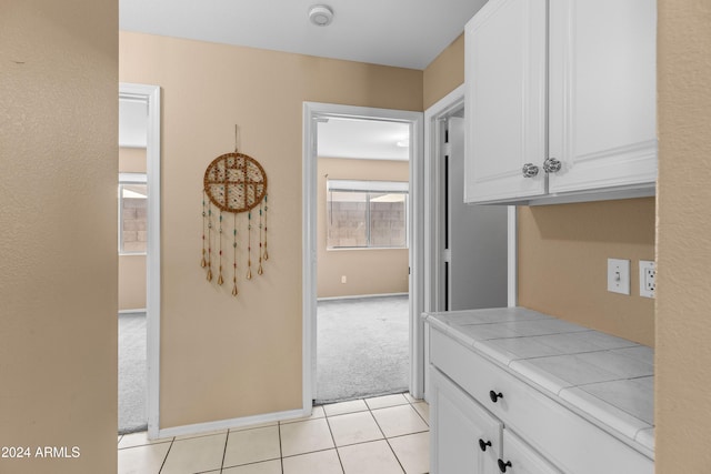 kitchen featuring white cabinets, light colored carpet, and tile counters