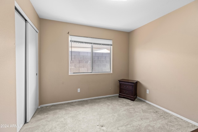 unfurnished bedroom with a closet and light colored carpet