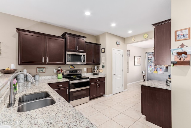 kitchen featuring sink, light tile patterned floors, appliances with stainless steel finishes, dark brown cabinets, and light stone countertops