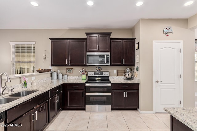 kitchen with light tile patterned flooring, sink, dark brown cabinets, stainless steel appliances, and light stone countertops