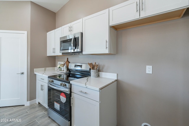 kitchen featuring white cabinets, light stone counters, and appliances with stainless steel finishes