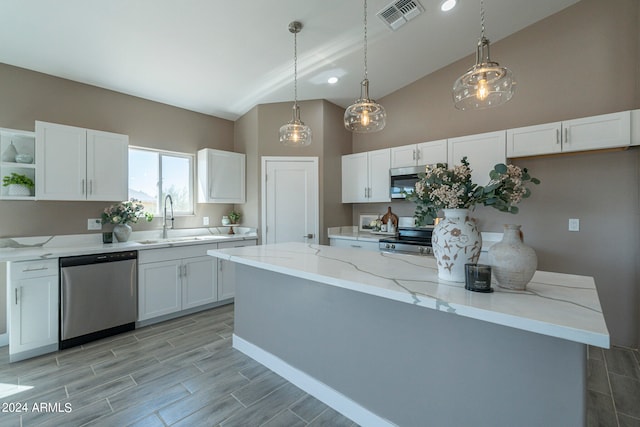 kitchen featuring sink, decorative light fixtures, light stone counters, white cabinetry, and stainless steel appliances