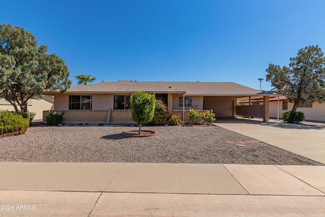 ranch-style house with a carport, concrete driveway, and brick siding