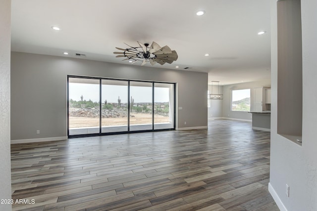 unfurnished room with dark wood-type flooring and ceiling fan with notable chandelier