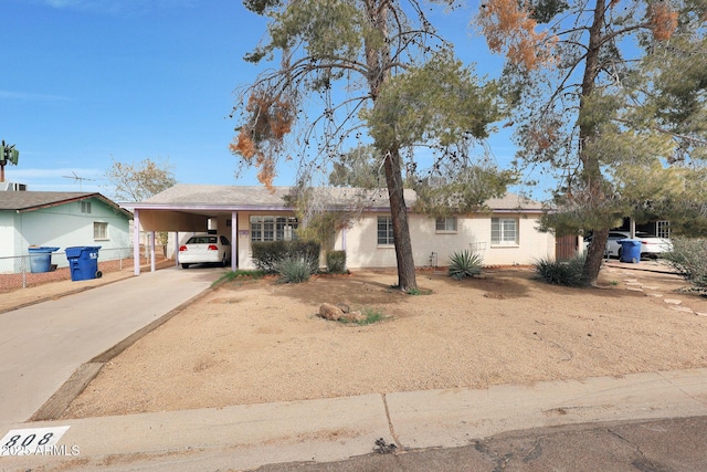 single story home with driveway, an attached carport, and fence