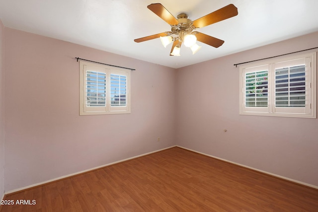 empty room featuring wood finished floors, a ceiling fan, and baseboards