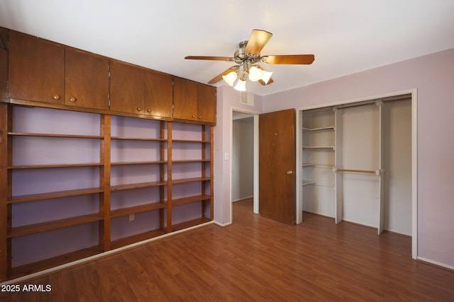 unfurnished bedroom with dark wood-style floors, a closet, visible vents, and a ceiling fan