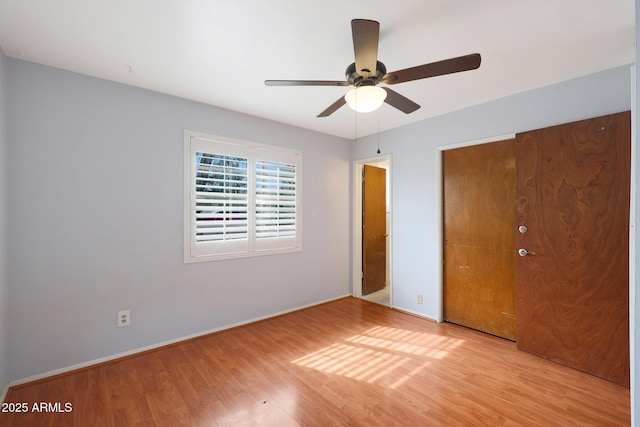 unfurnished bedroom featuring baseboards, light wood-style flooring, a ceiling fan, and a closet