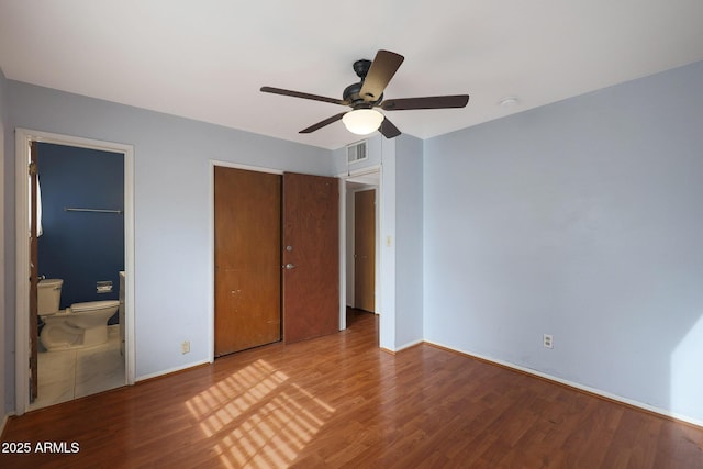 unfurnished bedroom with visible vents, ensuite bathroom, baseboards, and wood finished floors