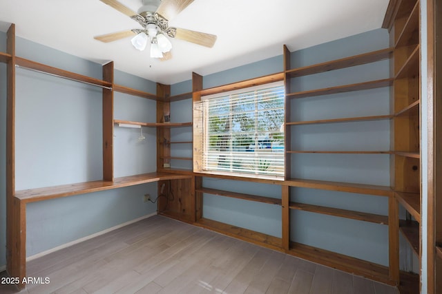 interior space featuring built in desk, a ceiling fan, and wood finished floors