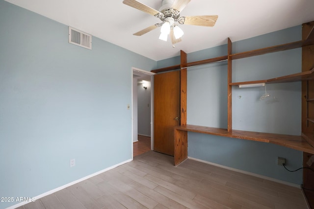 unfurnished bedroom featuring wood finished floors, a ceiling fan, visible vents, baseboards, and a closet