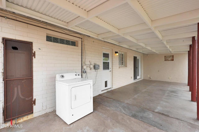 laundry area featuring brick wall and washer / clothes dryer