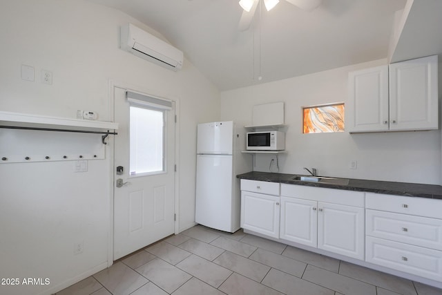 kitchen with white appliances, dark countertops, lofted ceiling, an AC wall unit, and a sink