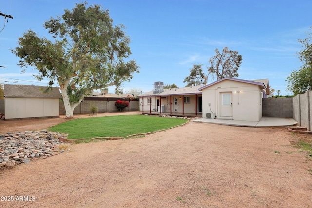 back of house featuring a patio, a fenced backyard, an outbuilding, a storage unit, and a yard