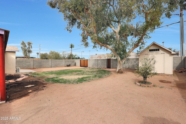 view of yard featuring an outbuilding, a storage unit, and a fenced backyard