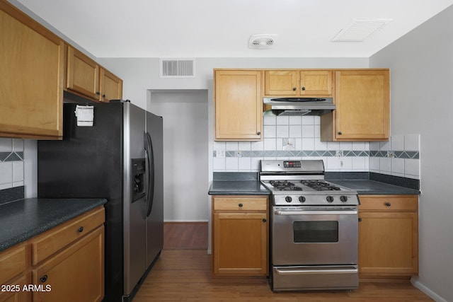 kitchen with dark countertops, under cabinet range hood, visible vents, and appliances with stainless steel finishes