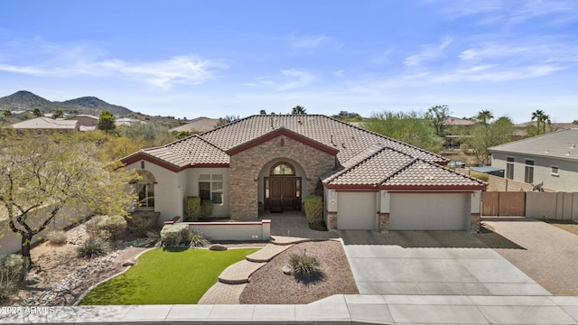 mediterranean / spanish home with stucco siding, concrete driveway, an attached garage, stone siding, and a tiled roof