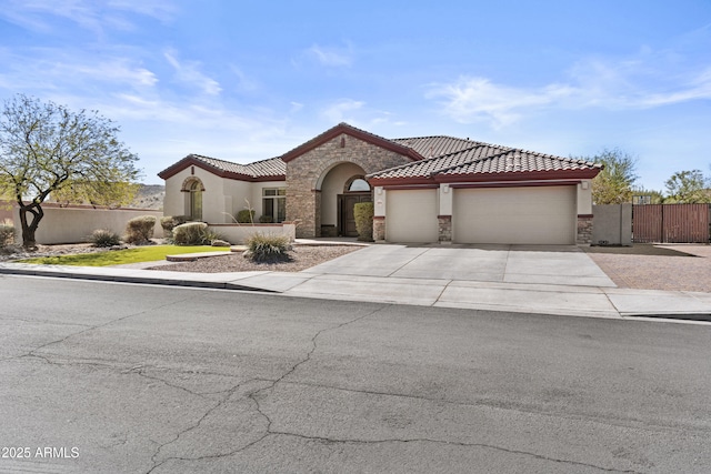 mediterranean / spanish house with a garage, stone siding, fence, and a tiled roof