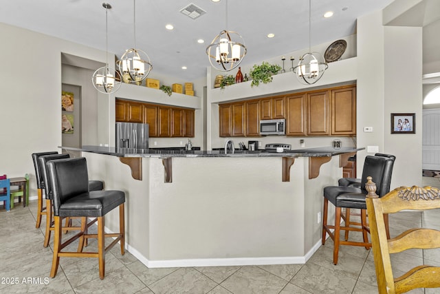 kitchen featuring appliances with stainless steel finishes, a breakfast bar, brown cabinets, and visible vents