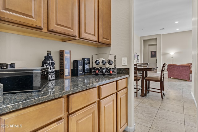 kitchen with dark stone countertops, light tile patterned flooring, and recessed lighting