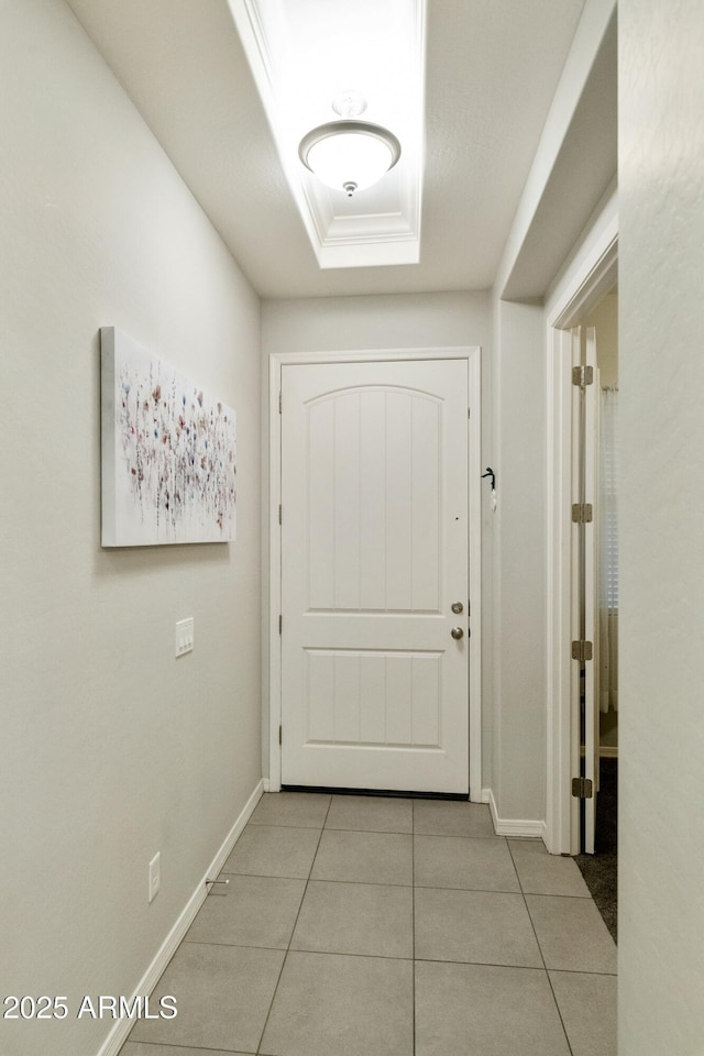 doorway to outside with light tile patterned floors, a raised ceiling, and ornamental molding