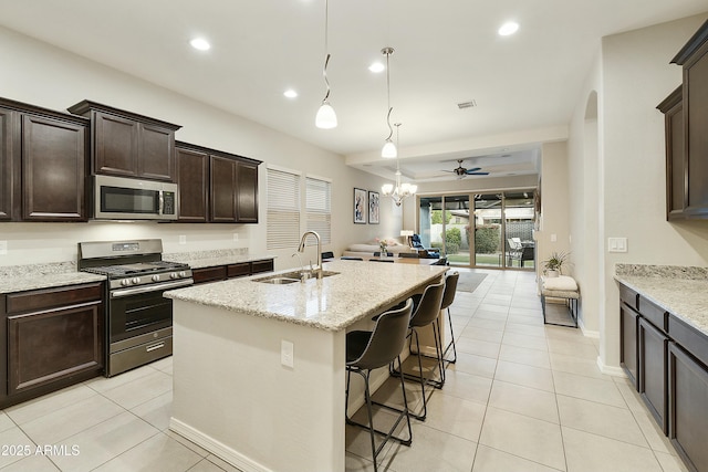 kitchen featuring sink, light stone counters, a breakfast bar area, a kitchen island with sink, and appliances with stainless steel finishes