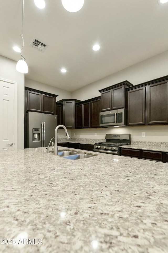 kitchen featuring dark brown cabinets, stainless steel appliances, hanging light fixtures, and sink