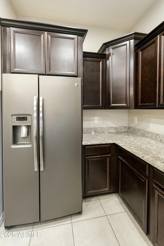 kitchen featuring light stone countertops, stainless steel fridge, dark brown cabinetry, and light tile patterned flooring