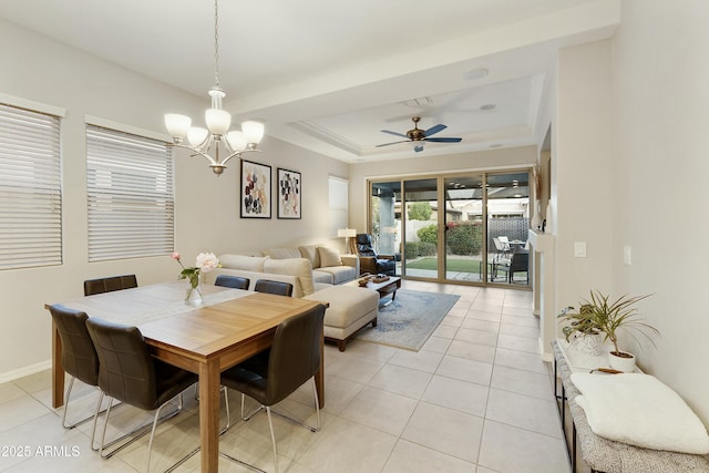 tiled dining space featuring a raised ceiling and ceiling fan with notable chandelier