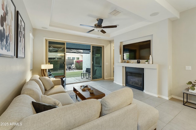 tiled living room with a tray ceiling and ceiling fan